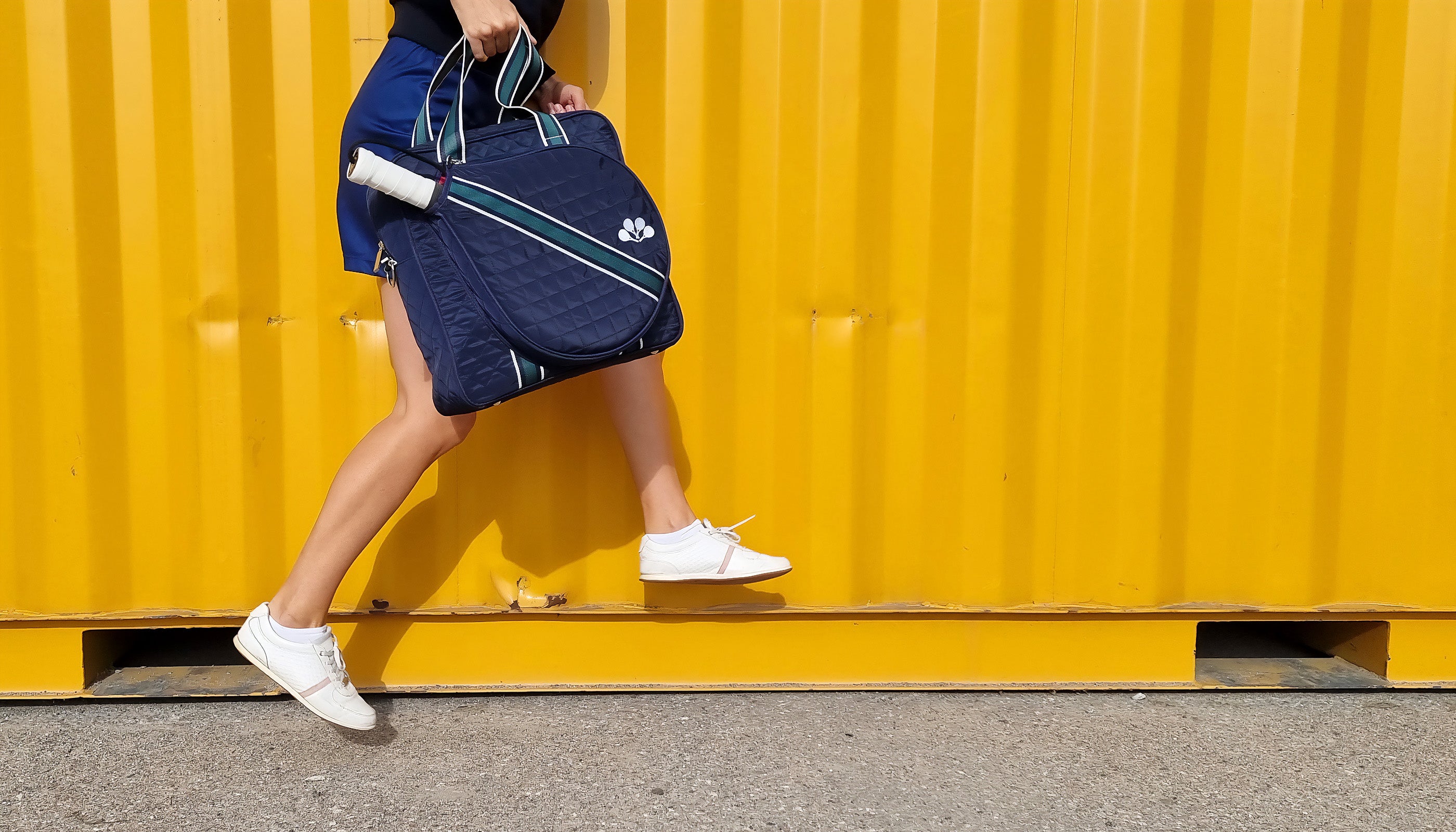 Person jumping with a blue paddle tennis bag with bright yellow background
